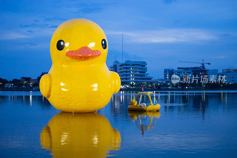 晚上，在Nong Prajak公园的湖面上，黄色的巨型充气鸭子和黄色的小船